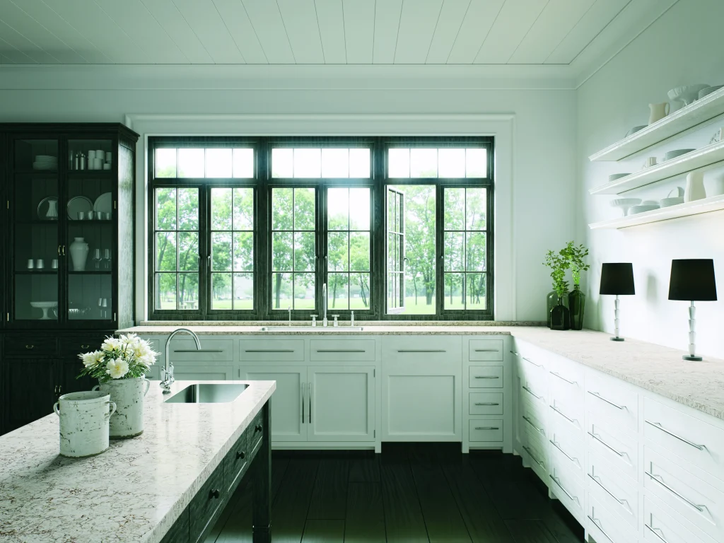 Deep green kitchen with pale quartz worktops and large windows